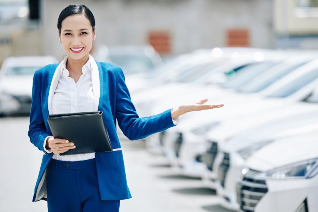 Who owns Big Motoring World. Female yong dealership manager inviting customers