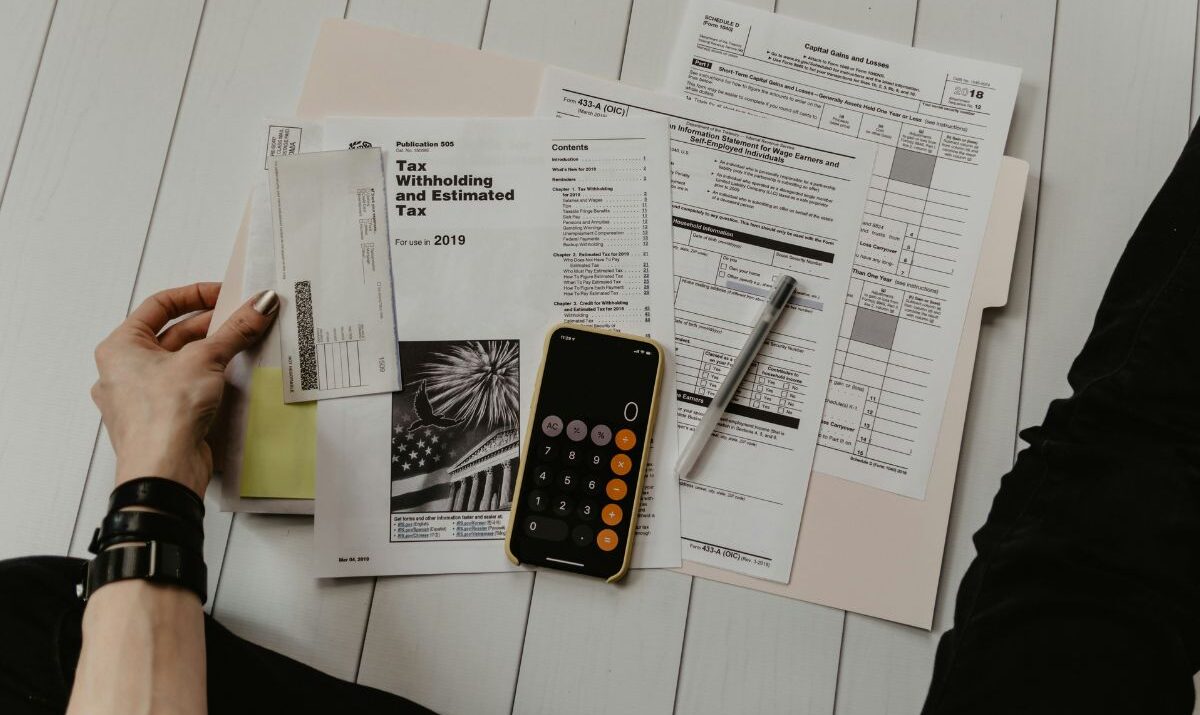 Stack of paper with someone doing their taxes. Arkansas Income Tax Rate article