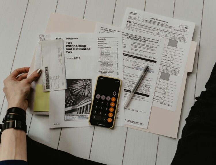 Stack of paper with someone doing their taxes. Arkansas Income Tax Rate article