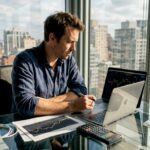 Man updating investment charts in sunlit office