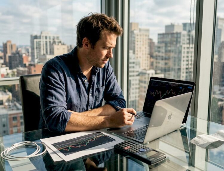 Man updating investment charts in sunlit office