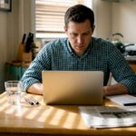Investor reviews portfolio at sunlit kitchen table