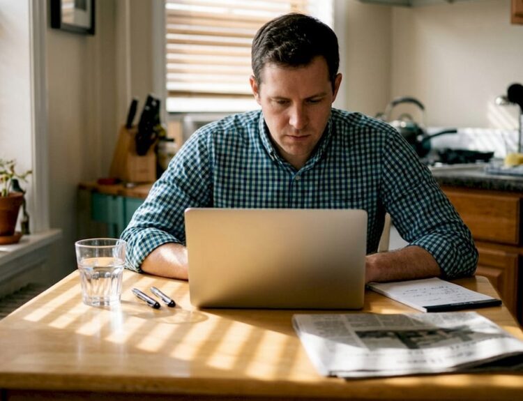 Investor reviews portfolio at sunlit kitchen table