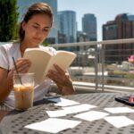 Young woman reading investing book at kitchen table