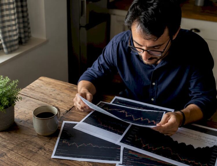 Investor studying printed stock market charts