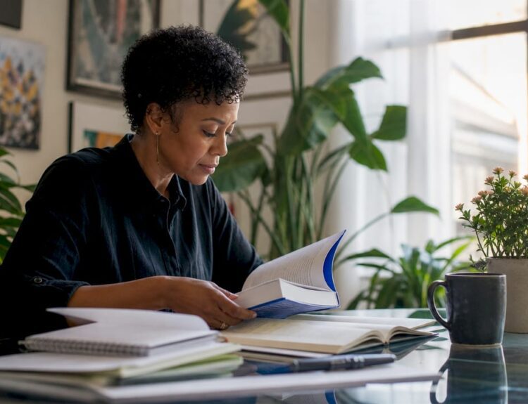 Woman reading investing books at home library desk