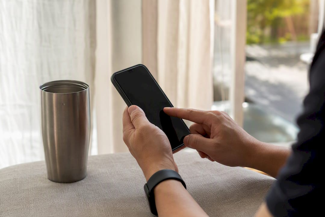 Hands interacting with smartphone to automate savings