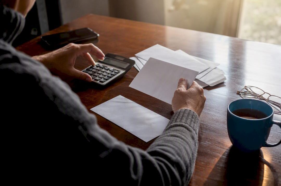 Hands calculating debts with cards and calculator