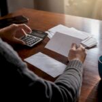 Hands calculating debts with cards and calculator