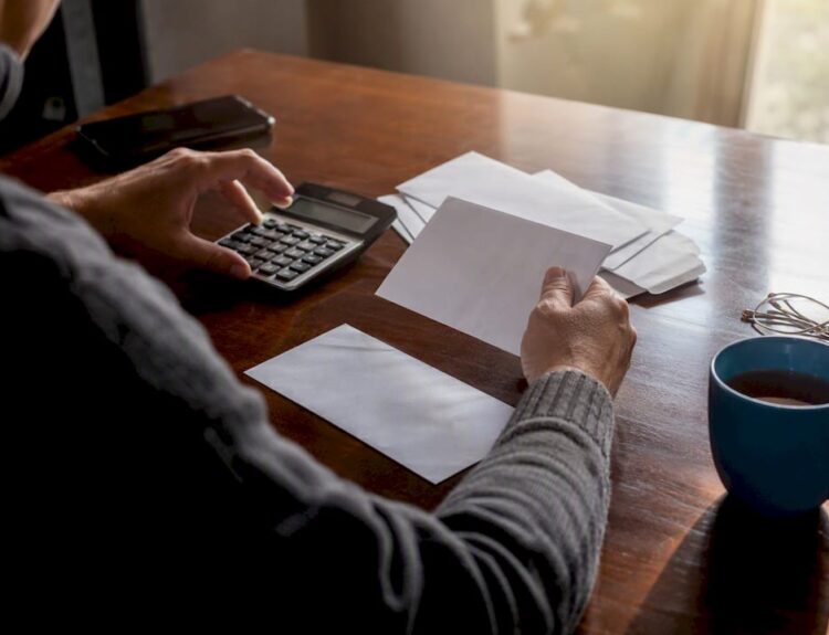 Hands calculating debts with cards and calculator